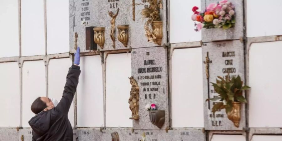 Frau mit Schutzmaske auf einem Friedhof in Madrid