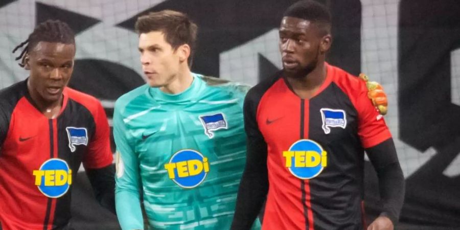 Herthas Dedryck Boyata (l-r) und Rune Jarstein nehmen Jordan Torunarigha vor der Schalker Nordkurve in Schutz. Foto: Bernd Thissen/dpa