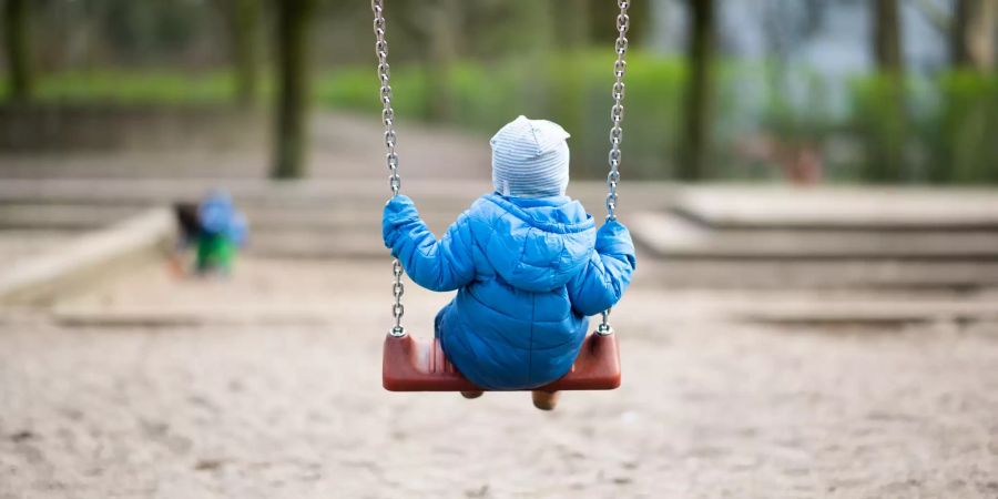 Ein Kleinkind schaukelt auf einem Spielplatz. Wegen des Coronavirus sind alle Schweizer Schulen geschlossen.