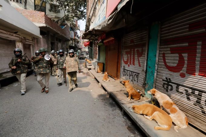 26.02.2020, Indien, New Delhi: Indische Sicherheitsbeamte patrouillieren auf einer Strasse, nach Protesten gegen das Einbürgerungsgesetz, das nach Ansicht von Kritikern gezielt Muslime diskriminiert. meta