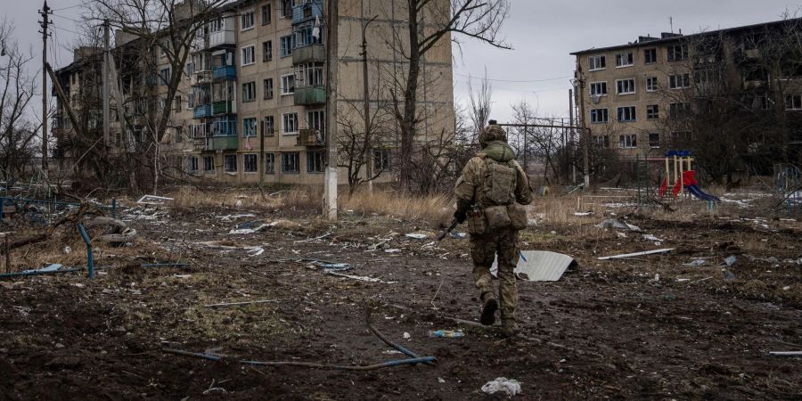 Ein ukrainischer Marinesoldat geht in Wuhledar an zerstörten Wohnblocks vorbei.