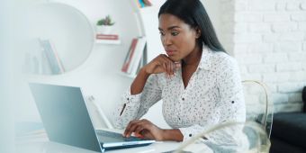 Frau sitzt am Schreibtisch und arbeitet mit dem Laptop