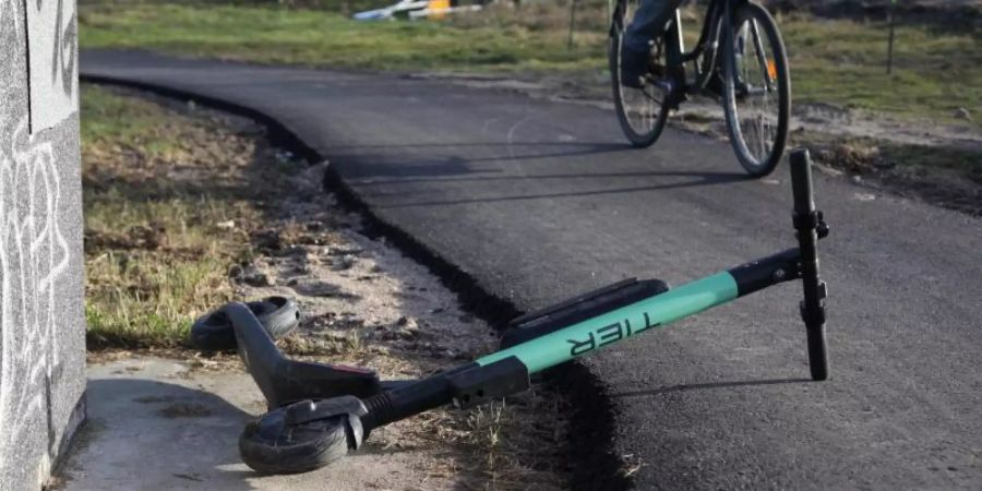 Ein Radfahrer weicht auf einem Radweg einem umgekippten E-Tretroller aus. Foto: Steffen Trumpf