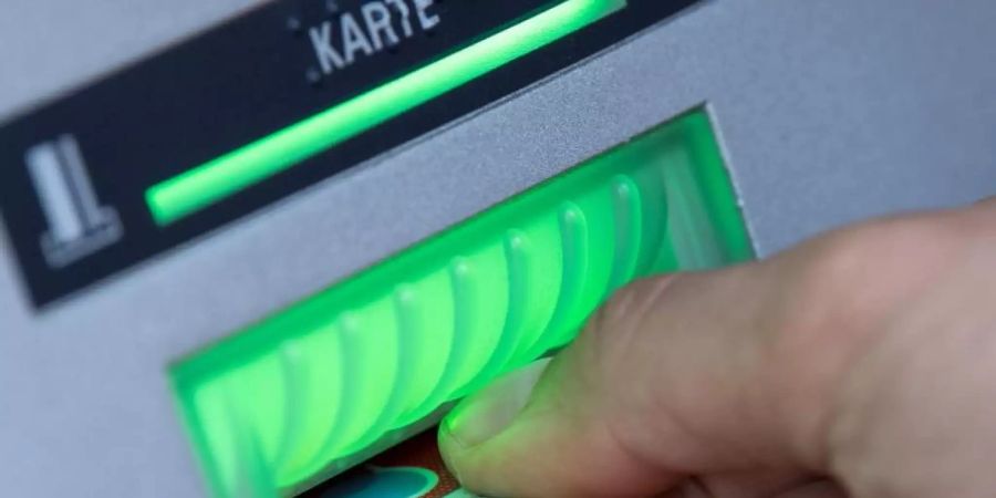 Eine Bankkundin steckt ihre Girokarte in einen Geldautomaten. Foto: Fabian Sommer/dpa