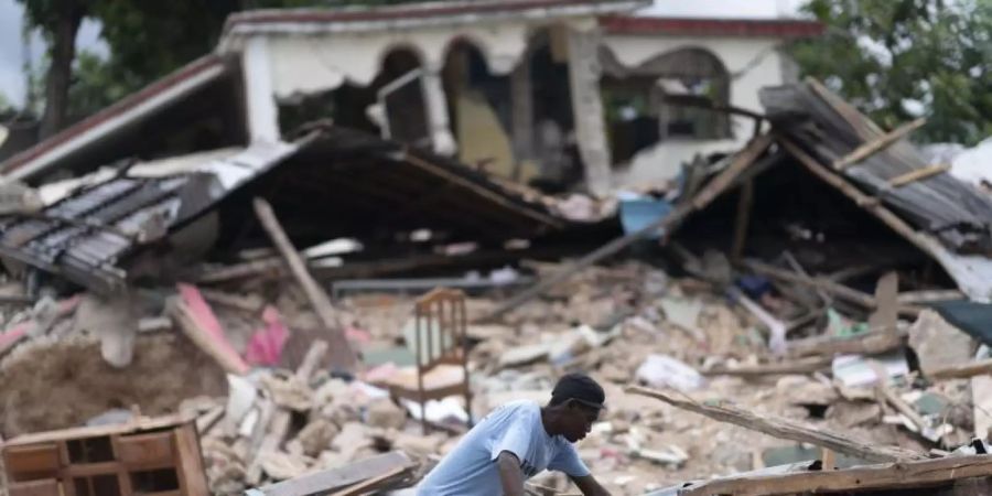 Ein Mann in den Trümmern eines eingestürzten Hause. Nach dem Erdbeben in Haiti ist die Zahl der bestätigten Todesopfer auf fast 2000 gestiegen. Foto: David de la Paz/XinHua/dpa