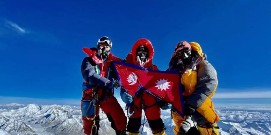 Nima Lhamu Sherpa (M) steht mit ihren Brüdern auf dem Gipfel des Mount Everest. Foto: Grace Best/Nima Lhamu Sherpa/dpa