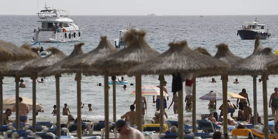 Gäste liegen am Strand von Paguera auf Mallorca. Nach der angekündigten Hochstufung Spaniens zum Corona-Hochinzidenzgebiet gibt es zunächst keine Hinweise, dass viele Menschen ihren Urlaub vorzeitig abbrechen oder gebuchte Aufenthalte stornieren wollen. Foto: Clara Margais/dpa