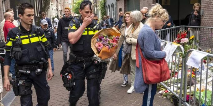 Polizisten bringen einen Blumenstrauss zu dem Blumenmeer für den Reporter Peter R. de Vries in der Leidswarsstraat. Foto: Evert Elzinga/ANP/dpa reporter