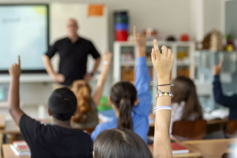 Schüler strecken ihre Hände auf in einer Primarklasse im Schulhaus Neuenhof im Kanton Aargau.