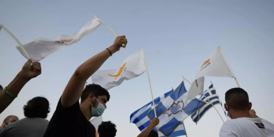 Bewohner der verlassenen Stadt Varosha oder Famagusta halten zypriotische und griechische Fahnen während eines Protestes gegen den türkischen Präsidenten Erdogan. Foto: Petros Karadjias/AP/dpa