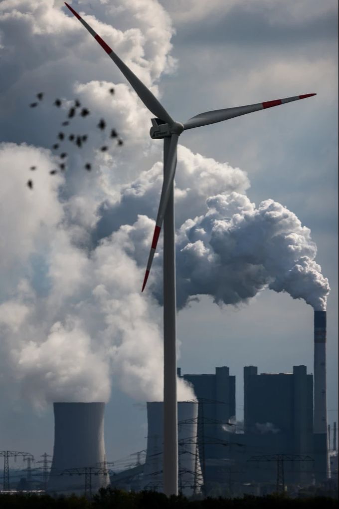 Ein Windrad dreht sich vor der Kulisse des Braunkohlekraftwerks Schkopau, westlich von Halle (D), während ein Vogelschwarm vorbeizieht. Vögel Windkraftwerk fossile Energie