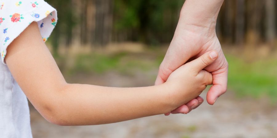 mutter und kind halten händchen in der natur