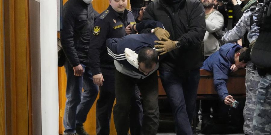 Ein Tatverdächtiger des Terroranschlags auf die Konzerthalle Crocus City Hall wird von Polizisten und FSB-Beamten im Basmanny-Bezirksgericht eskortiert. Foto: Alexander Zemlianichenko/AP