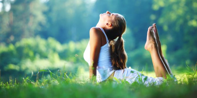 Frau praktiziert draussen Yoga.