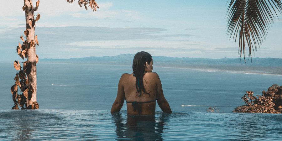 Frau im Infinitypool mit Blick aufs Meer.