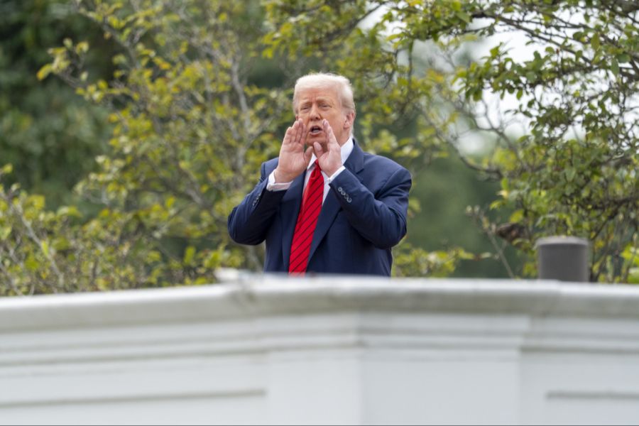 Donald Trump ruft Reportern vom Dach des Weissen Hauses etwas zu.