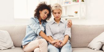 Zwei junge Frauen auf einem Sofa, Trost, Trauer