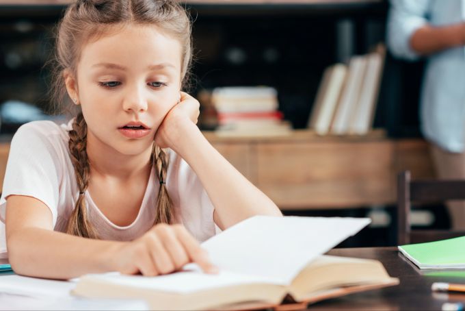 Buchstaben und Wörter verschwimmen: Dyslexie erschwert das Lesen und Schreiben. Junges Mädchen liest Buch