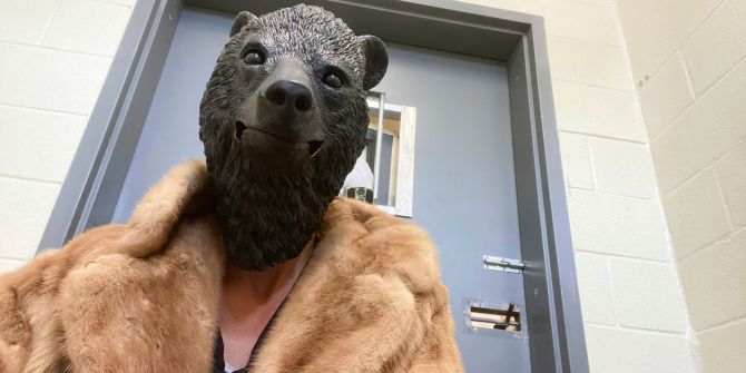 Bärenmaske, Pelzmantel, mit Laub gespickte Kapuzen
