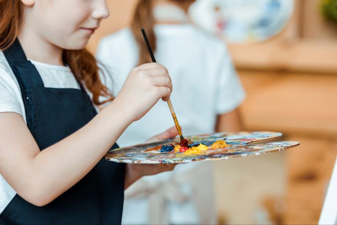 Wer Kindern die Freiheit lässt, Neues auszuprobieren, fördert Kreativität, Selbstvertrauen und Eigenständigkeit. Junges Mädchen mit Farben und Pinsel