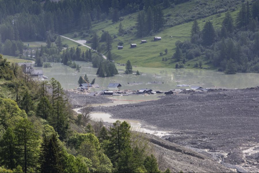 Die Lonza überströmt Schlamm und Geröll bei den letzten Häusern von Blatten, einen Tag nach dem verheerenden Gletschersturz.