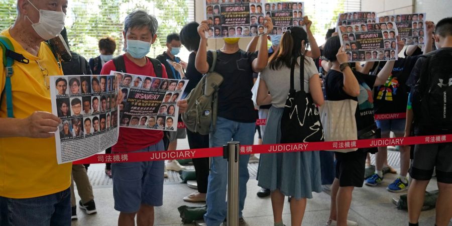 Unterstützer halten vor einem Gericht in Hongkong Plakate mit den Fotos einiger der 47 angeklagten Demokratie-Aktivisten in die Höhe.