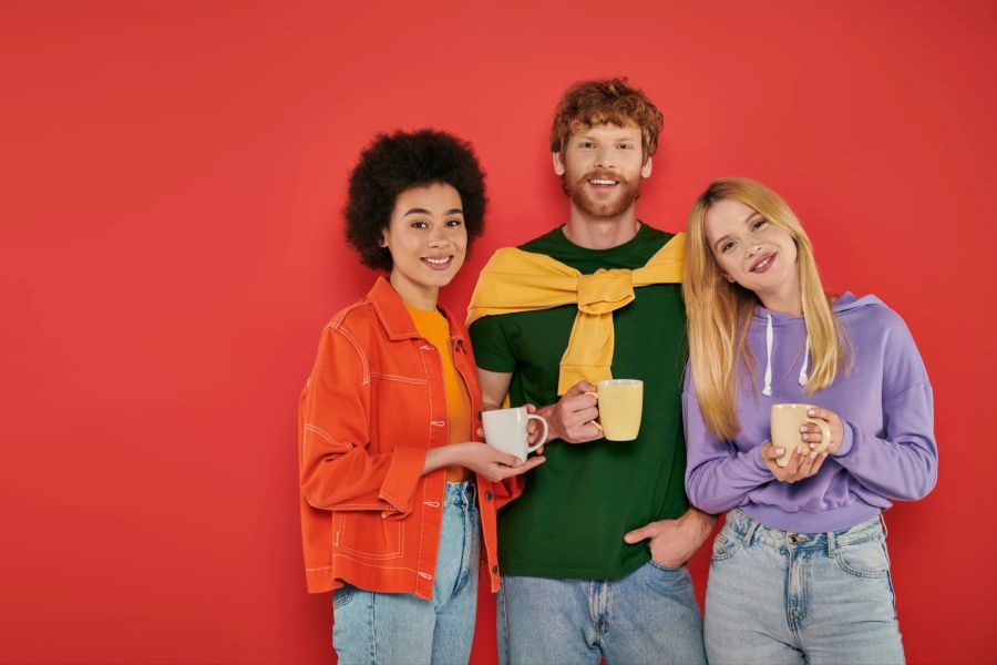 mann mit zwei frauen vor rotem hintergrund, kaffee-trinkend