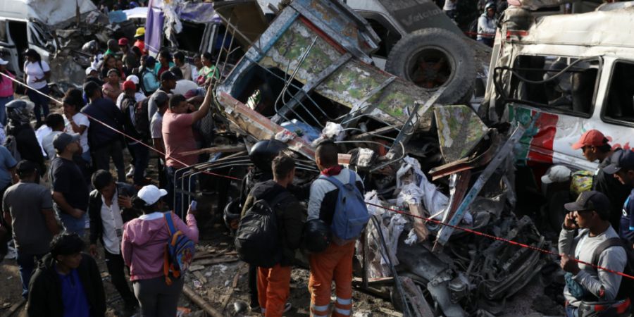 Menschen versammeln sich um Fahrzeuge, die bei einem Anschlag auf der Panamericana beschädigt wurden. Gut einen Monat vor der Präsidentenwahl in Kolumbien sind bei einem Bombenanschla...