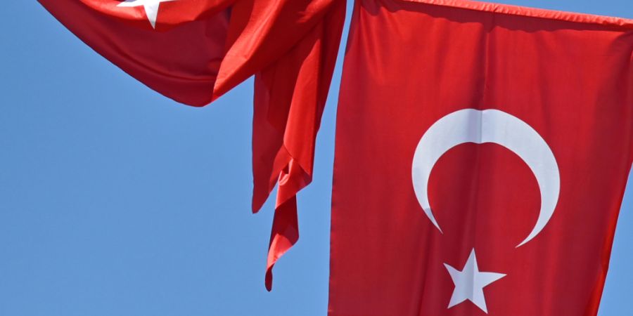 ARCHIV - Eine türkische Flagge weht vor blauem Himmel im Wind, während eine zweite Flagge aufgewickelt daneben hängt. Foto: Anna Ross/dpa
