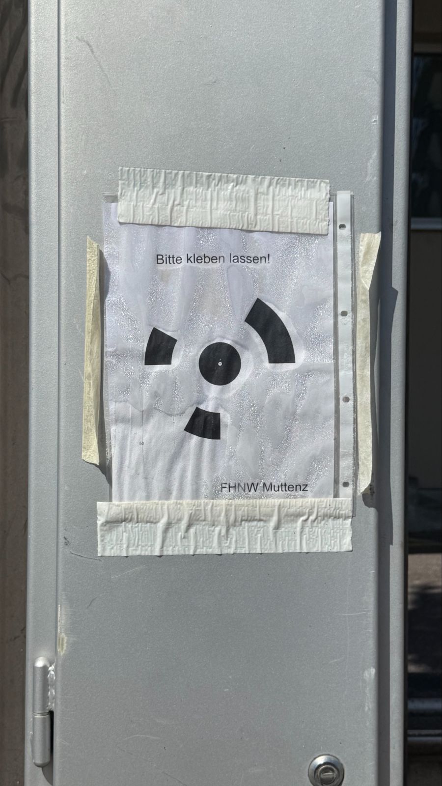 Mehrere A4-Blätter hängen unweit des Fachhochschulen-Campus in Muttenz.