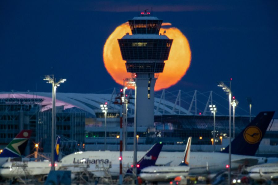 Der Blutmond steht hinter dem Tower des Münchner Flughafens.