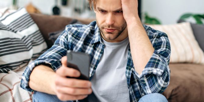 Verzweifelter Mann schaut auf sein Smartphone