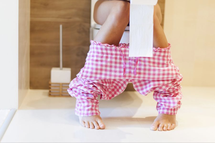 Person sitzt auf der Toilette