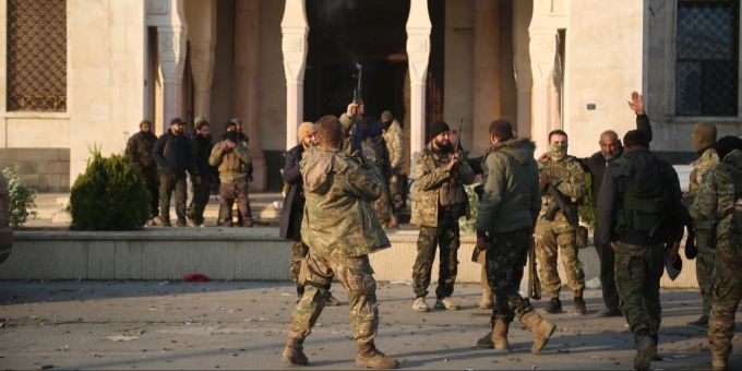 Oppositionskämpfer feuern vor einem Regierungsgebäude in Hama ihre Waffen in die Luft. Nahost