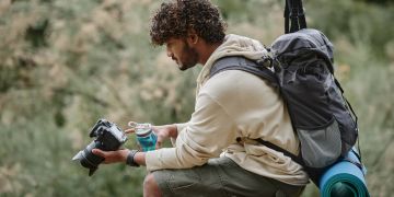 Lockiger Tourist mit professioneller Kamera und Wanderrucksack.