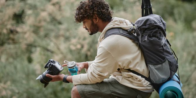 Lockiger Tourist mit professioneller Kamera und Wanderrucksack.