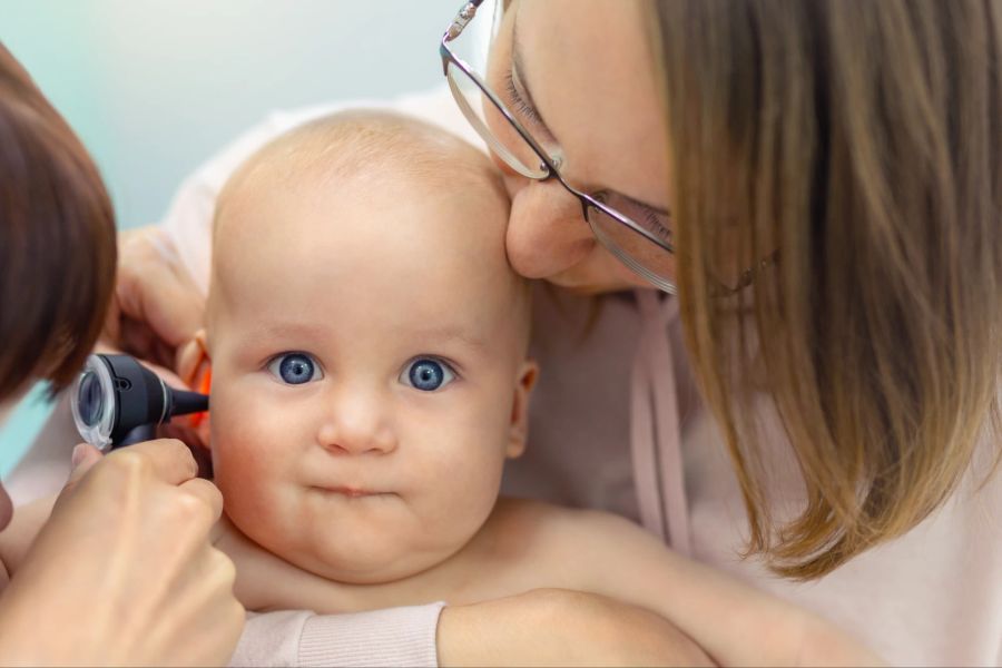 Stockfotografie Kinderarzt untersucht Kinderohr mit Otoskop.