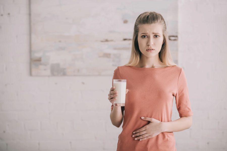 Frau hält sich den Bauch, nachdem sie Milch getrunken hat