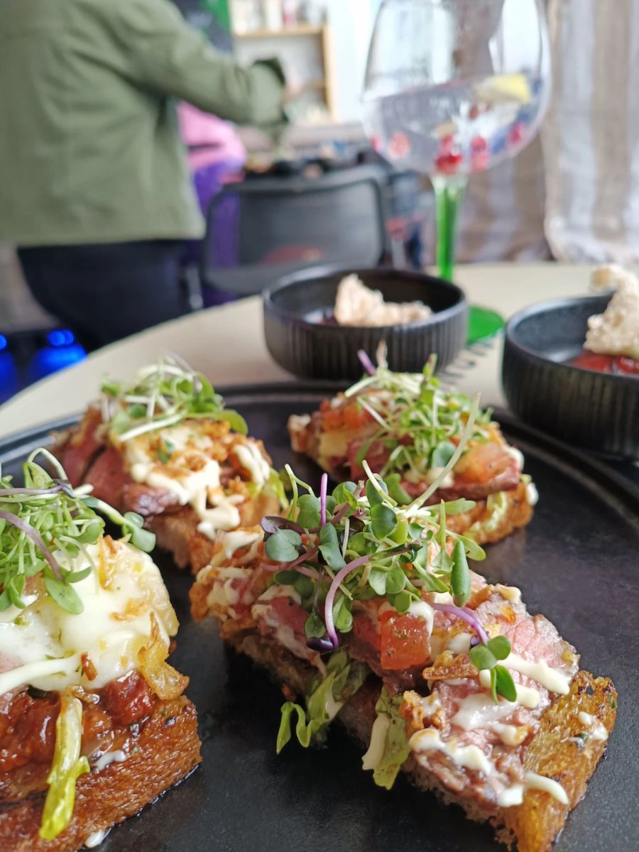 Steak vom Chuck Flap - Luma: Sauerteigbrot, Speck-Zwiebel-Confit, Tomaten-Kräuter-Salsa, rote Zwiebeln, Lattich, Raclette-Käse von Jumi, Mayonnaise und Röstzwiebeln