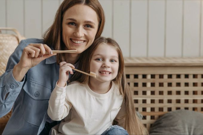 Schon Kinder können lernen, dass Nachhaltigkeit bei vielen Alltagsgegenständen möglich ist: auch bei Zahnbürsten. Kind Frau Mutter Zahnbürste Holz