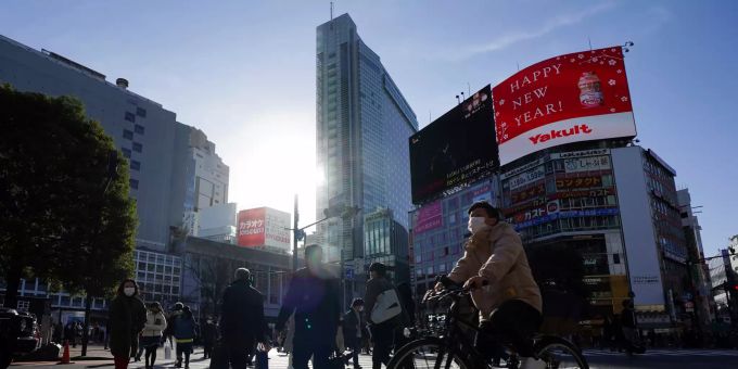 Menschen mit Mund-Nasen-Schutz überqueren die Strasse im Stadtteil Shibuya in Tokio. Coronavirus - Japan