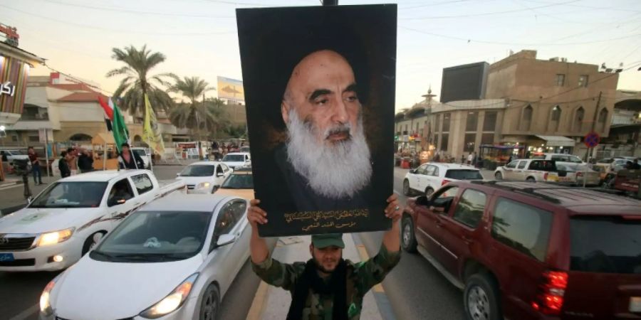 Ein Mann in Basra hält ein Porträt von Sistani in die Höhe