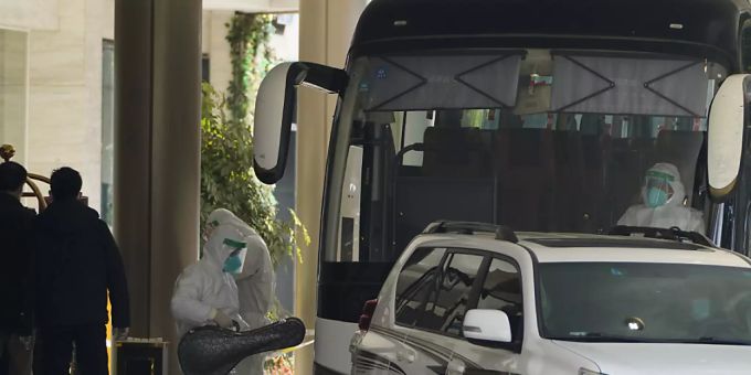ARCHIV - Ein Arbeiter in Schutzkleidung verlässt ein Quarantäne-Hotel in Richtung eines Busses und trägt ein Musikinstrument. Foto: Ng Han Guan/AP/dpa ARCHIV - Ein Arbeiter in Schutzkleidung verlässt ein Quarantäne-Hotel in Richtung eines Busses und trägt ein Musikinstrument. Foto: Ng Han Guan/AP/dpa