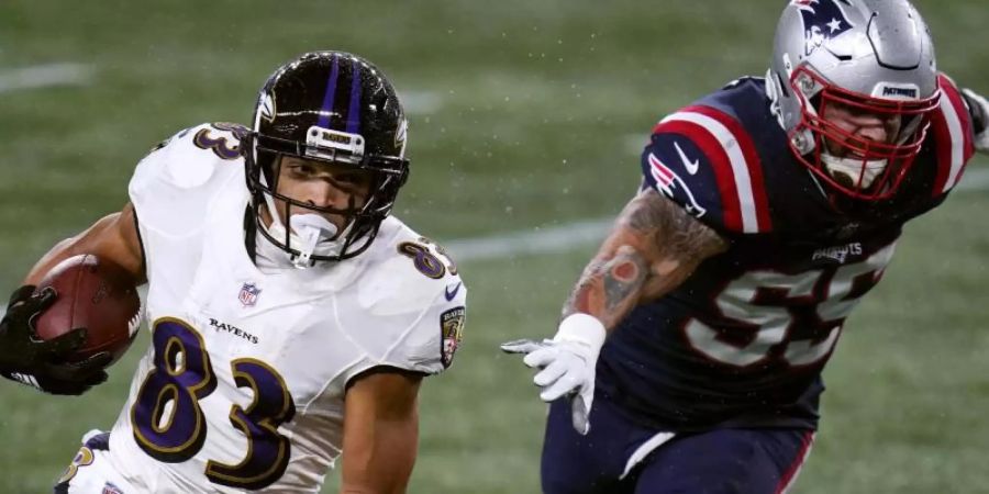 Willie Snead (l) von den Baltimore Ravens und John Simon von den New England Patriots sind in Aktion. Foto: Charles Krupa/AP/dpa