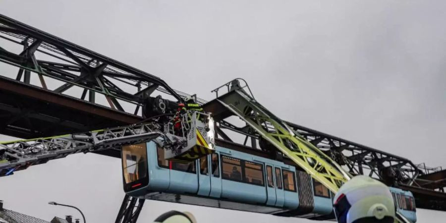 Einsatzkräfte der Feuerwehr befreien mit einer Drehleiter Fahrgäste aus einem Wagen der Schwebebahn, die wegen des eisigen Wetters stehen geblieben ist. Foto: Christoph Petersen/dpa