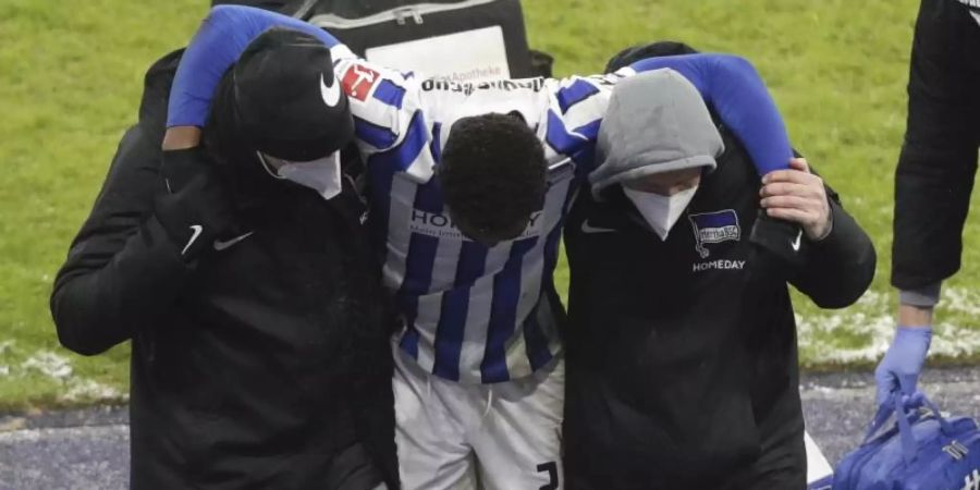 Herthas Jordan Torunarigha (M) wird nach einem Zusammenprall mit Bayerns Leroy Sane vom Platz gebracht. Foto: Michael Sohn/AP-Pool/dpa