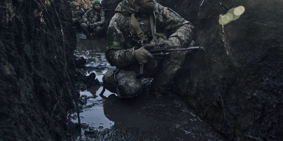 Unter russischem Beschuss hocken ukrainische Soldaten in einem Schützengraben an der Frontlinie nahe Bachmut. Foto: LIBKOS/AP/dpa