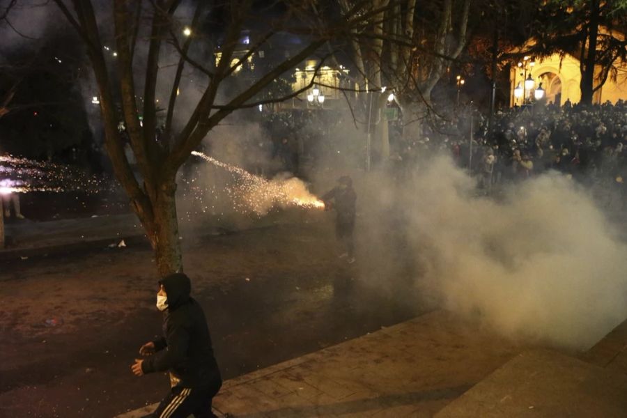 Ein Demonstrant benutzt einen Feuerwerkskörper während Zusammenstößen mit der Polizei vor dem georgischen Parlamentsgebäude in Tiflis, Georgien, Mittwoch, 8. März 2023. Die georgischen Behörden setzten am Dienstag Tränengas und Wasserwerfer vor dem Parlamentsgebäude in der Hauptstadt gegen Demonstranten ein, die sich gegen ein vorgeschlagenes Gesetz wehrten, das einige als Einschränkung der Pressefreiheit ansehen.