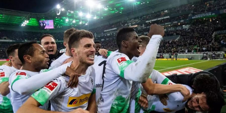 Die Gladbacher Spieler jubeln nach dem Treffer zum 2:1 durch Ramy Bensebaini (r). Foto: Marius Becker