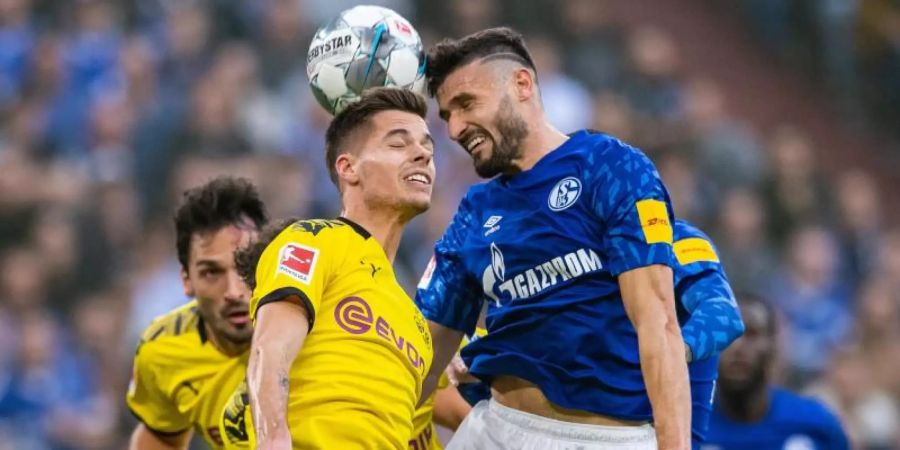Dortmunds Julian Weigl (l) und Schalkes Daniel Caligiuri kämpfen im Kopfballduell um den Ball. Foto: Guido Kirchner/dpa
